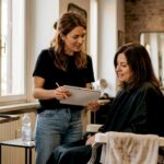 Personalizzazione nel taglio: guida per hairstylist 2026 Il parrucchiere ascolta le esigenze della cliente prima di iniziare il taglio.